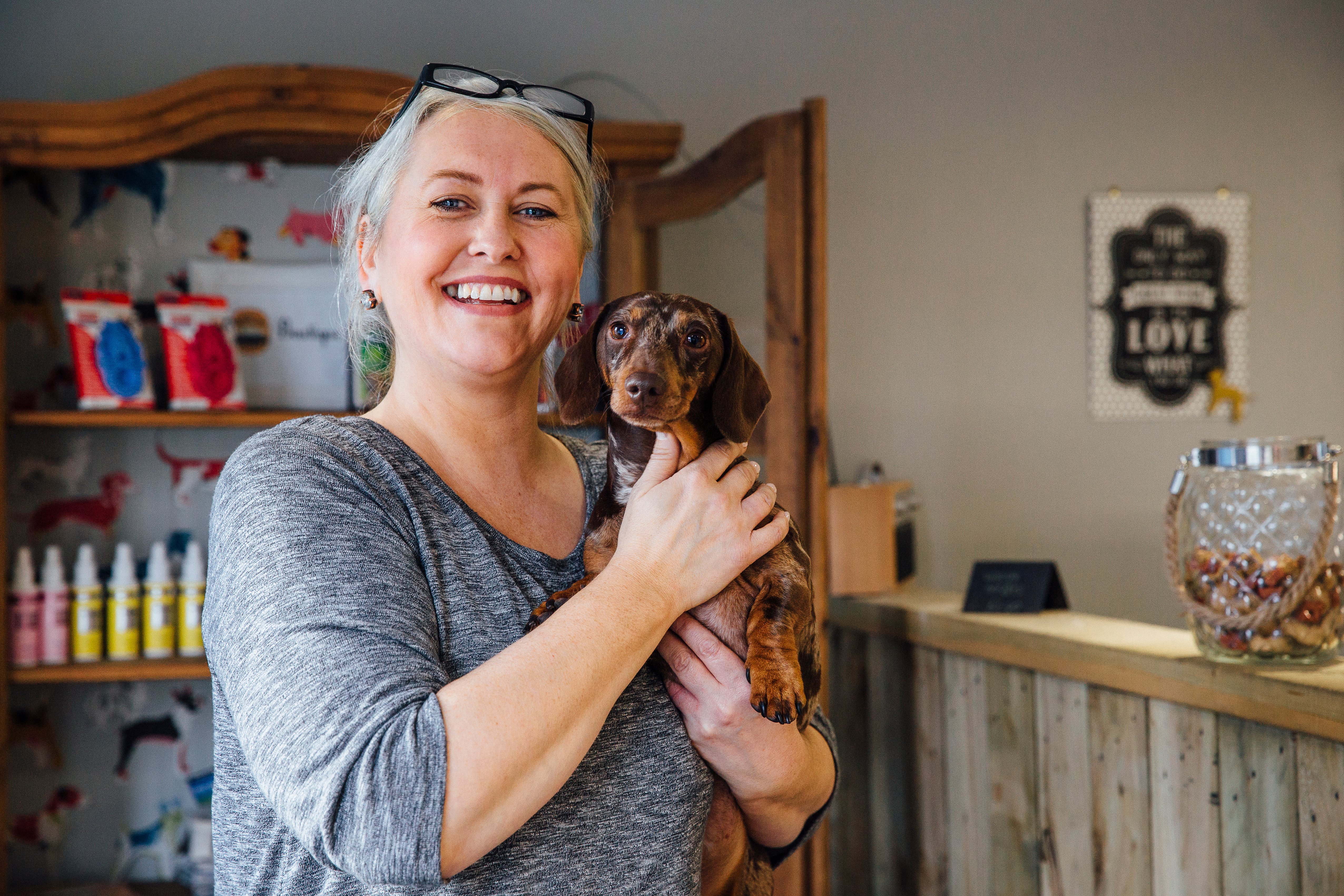 This image of a smiling woman holding a dog represents how investing in dog daycare software can help you keep your business fun. 