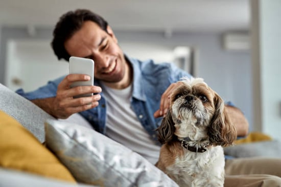 A man uses a phone while sitting with his dog