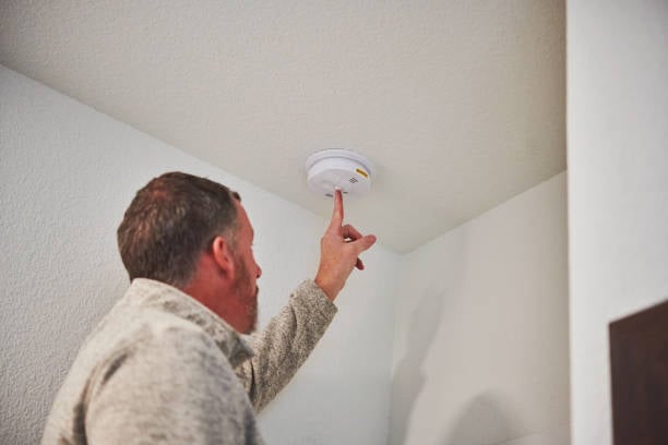 team member inspecting smoke detector in pet facility