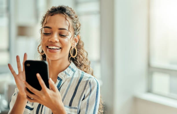 woman sending a delightful text about a pet and smiling