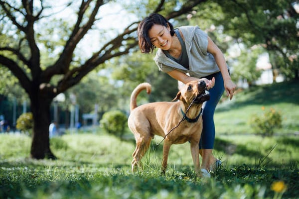 A woman plays with her dog outside