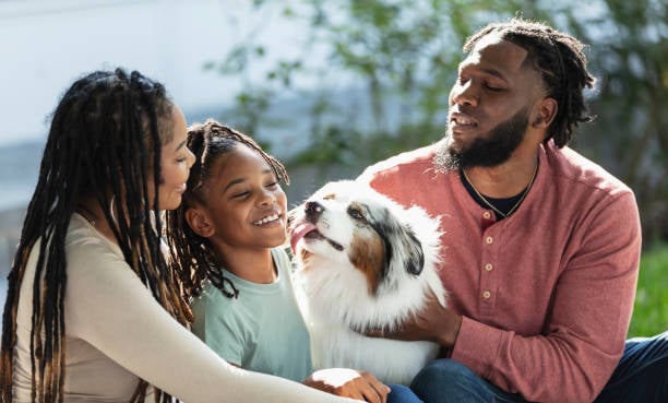 family smiling and posting with their pet dog