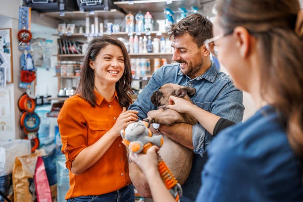 pet parents happily shopping for a dog toy with staff member