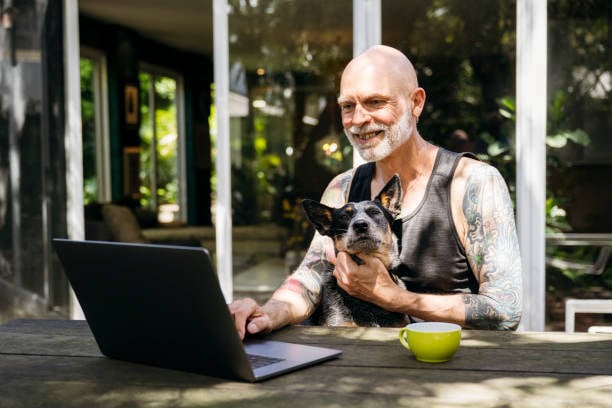 man sending email outside with dog on lap