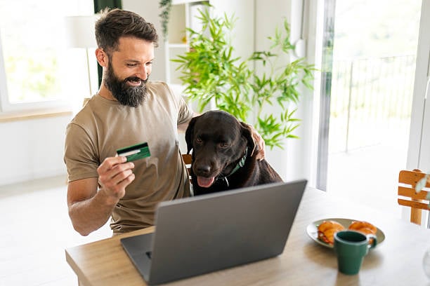 pet parent with credit card and laptop with dog