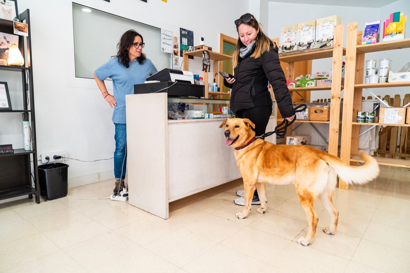 A staff member checking in a customer and their dog at the front desk of a pet-care business