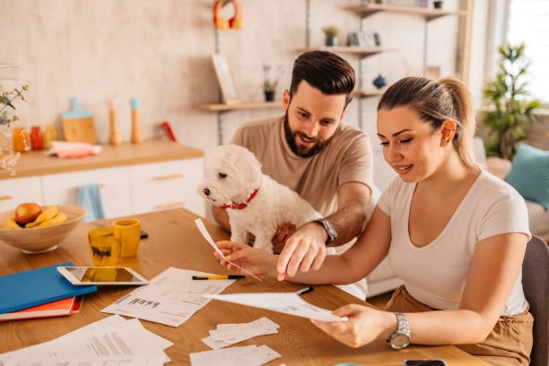 Two people examine paperwork while their dog sits with them